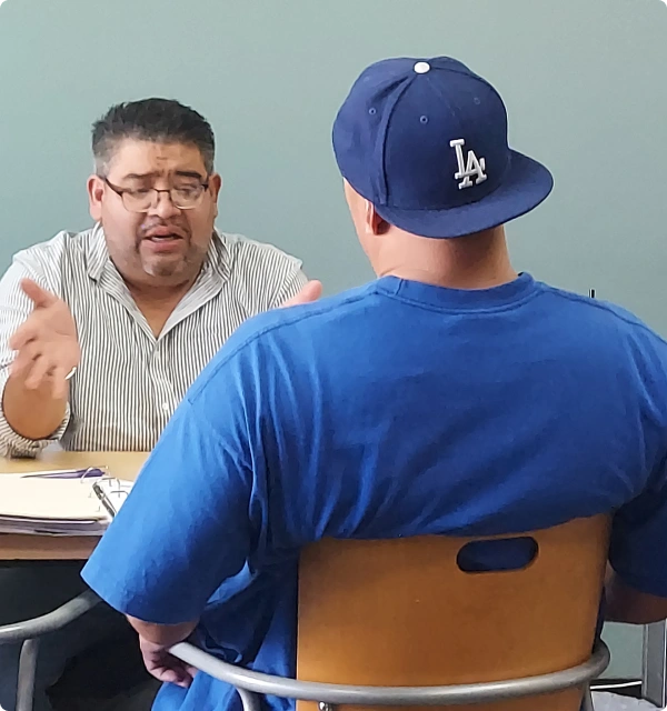 Abogado con gorra conversando con un cliente en una mesa