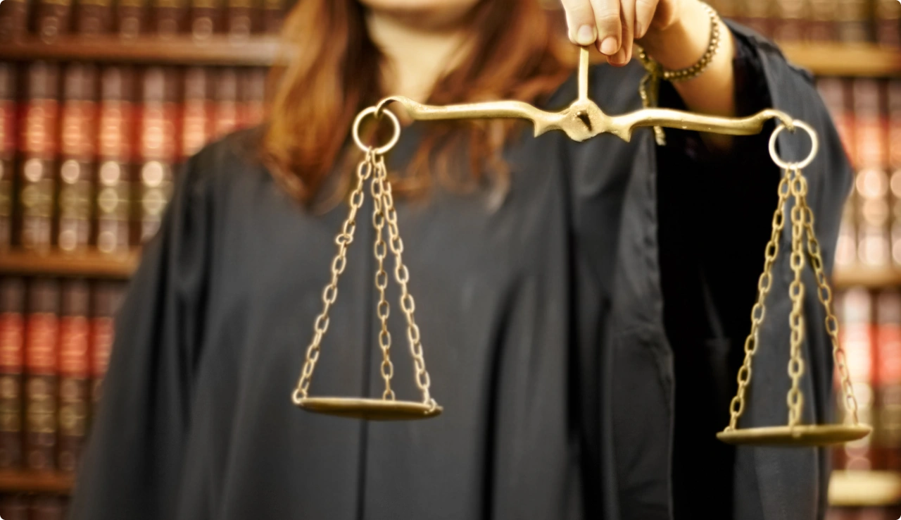 Persona con toga sosteniendo una balanza de la justicia