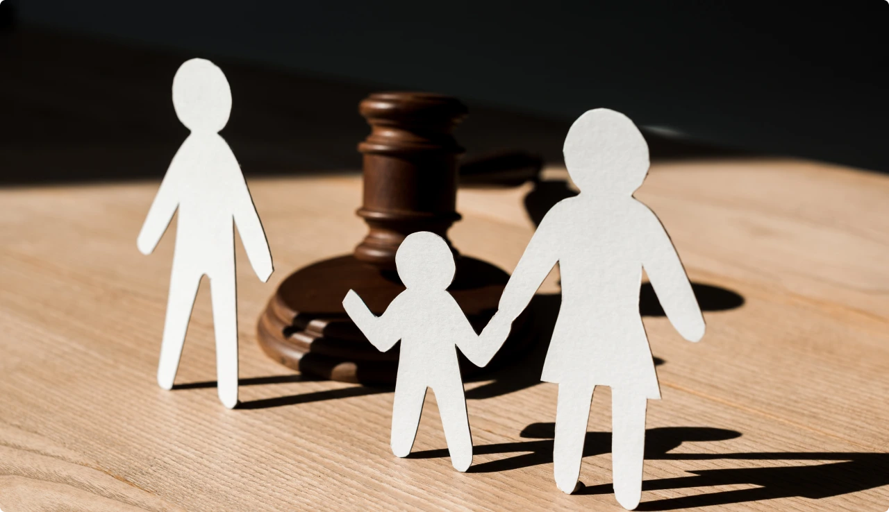 Figuras de papel de una familia junto a un mazo de juez