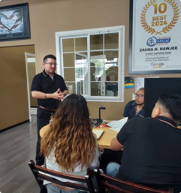 Reunión de abogados y clientes en una oficina con un certificado en la pared