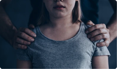 Manos de una persona sobre los hombros de una mujer asustada