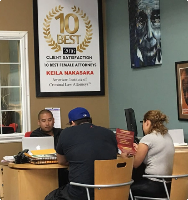 Oficina de abogados con un certificado de reconocimiento en la pared y clientes en el escritorio