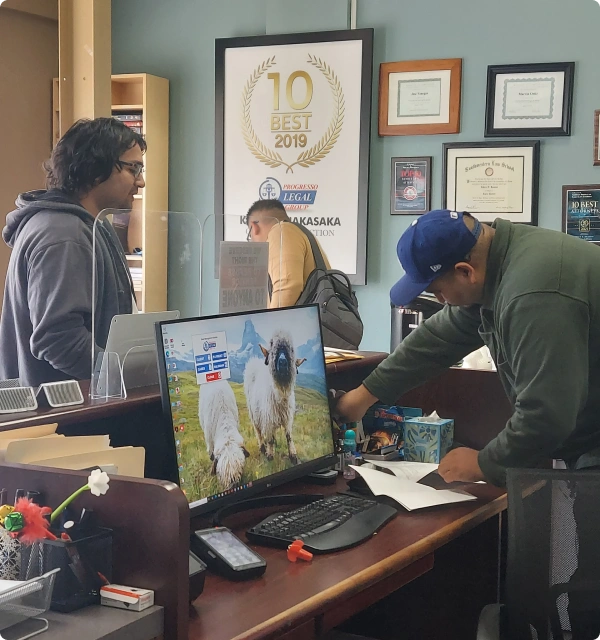 Persona usando una computadora en una oficina con diplomas en la pared