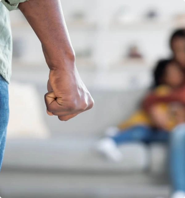 Puño cerrado en primer plano con una mujer y un niño desenfocados al fondo