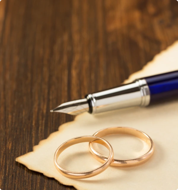 Pluma estilográfica y anillos de matrimonio sobre un documento