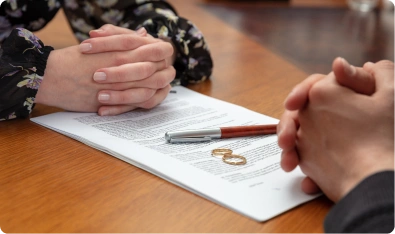 Manos entrelazadas sobre un documento y un anillo