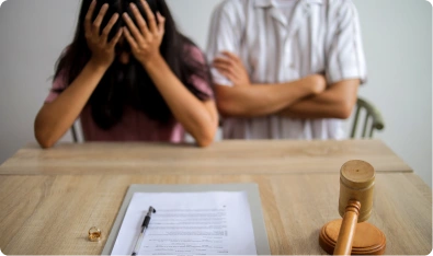 Mujer con las manos en el rostro junto a un hombre y un mazo de juez sobre la mesa