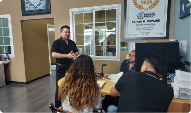 Oficina de abogados con clientes en el escritorio y un certificado en la pared