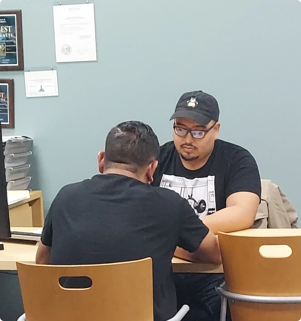 Abogado conversando con un cliente con gorra en una oficina