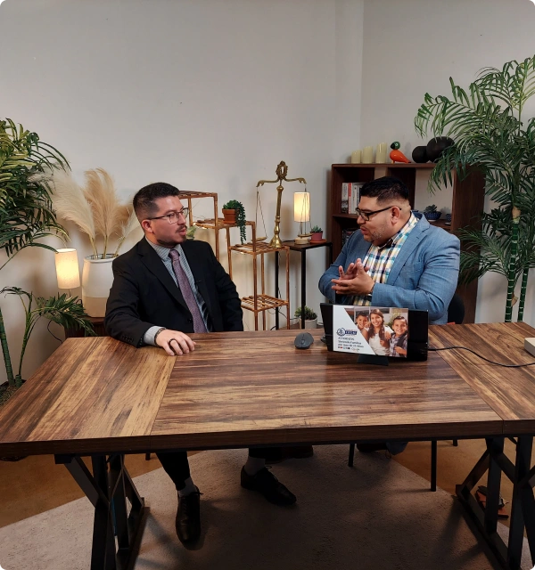 Dos abogados conversando en una mesa de madera en una oficina