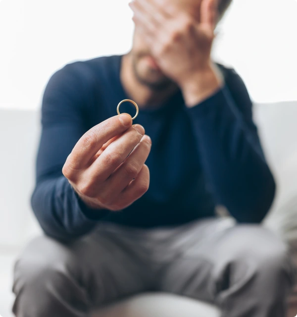 Hombre sosteniendo un anillo de bodas con la mano en el rostro