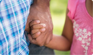 Adulto sosteniendo de la mano a una niña