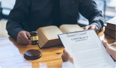 Contrato sobre un escritorio con un mazo de juez y un libro de leyes