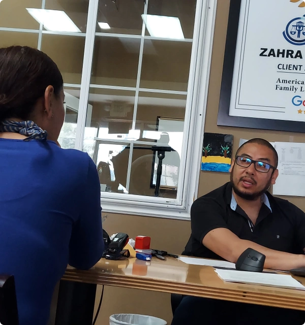 Abogado atendiendo a una clienta en una oficina con un certificado en la pared