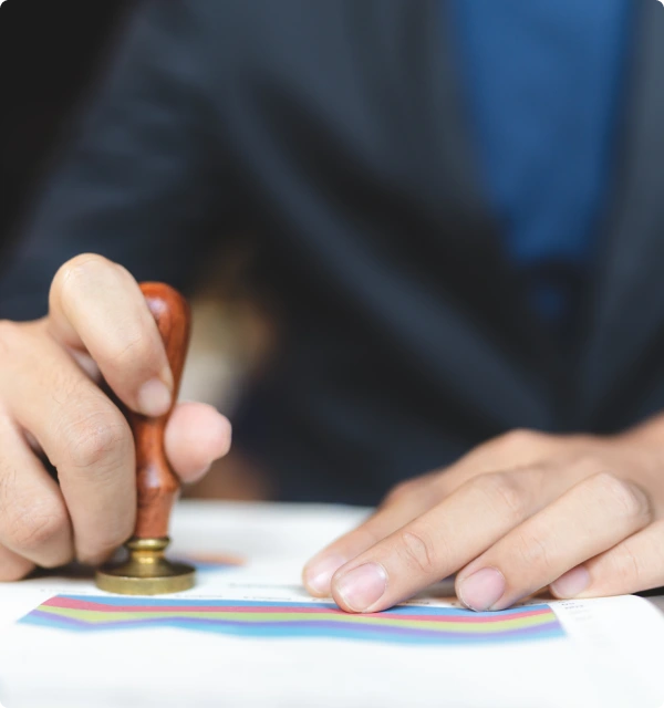 Manos aplicando un sello notarial sobre un documento