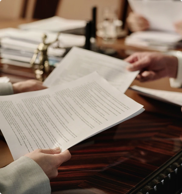 Manos revisando documentos legales sobre un escritorio
