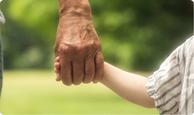 Mano de un adulto mayor sosteniendo la mano de un niño al aire libre