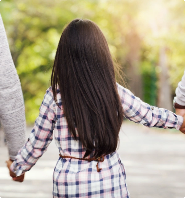 Niña caminando de la mano de un adulto