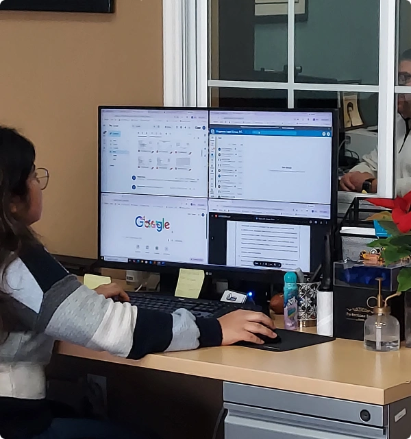 Persona trabajando frente a monitores de computadora en una oficina