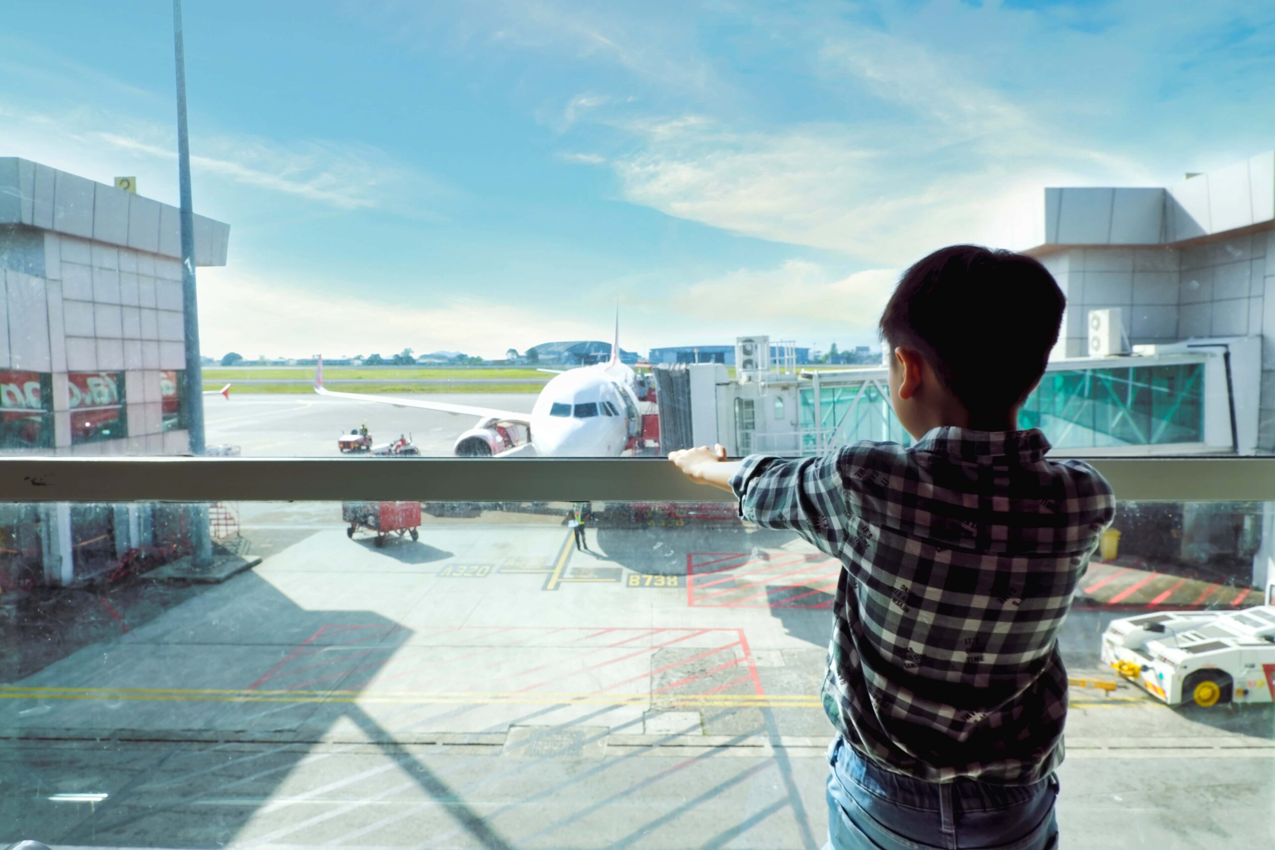 Niño mirando un avión en un aeropuerto a través de un ventanal