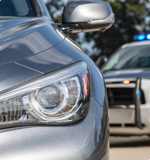 Auto gris con una patrulla de policía al fondo