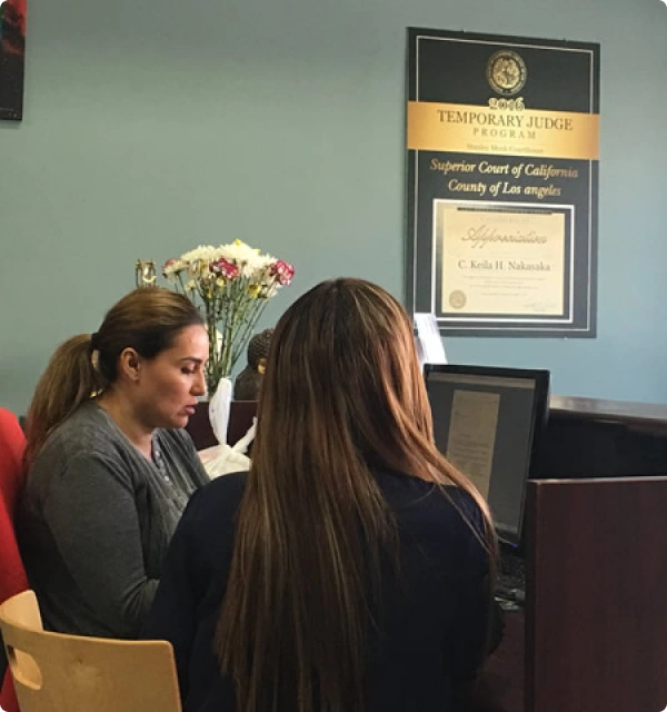 Dos mujeres atendidas en una oficina de abogados con un certificado en la pared